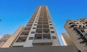 A high-rise building with multiple balconies, a clear sky, and adjacent structures. - Studio in Condo. w/ Balcony & City View Moe0312 (São Paulo)