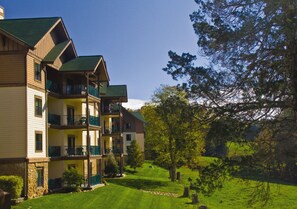 A multi-story building with balconies, surrounded by a well-maintained lawn and trees. - Sevierville | Pool & Mountains | 2BR Condo (Sevierville)