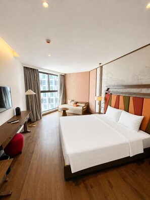 Habitación de hotel con cama, escritorio, silla, lámpara y ventana.