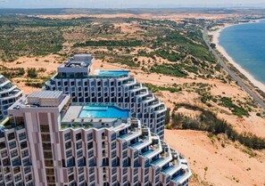 Un hotel de gran altura con varios balcones que dan a una playa y al océano.
