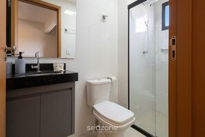 Uma casa de banho moderna com sanita, lavatório e chuveiro.