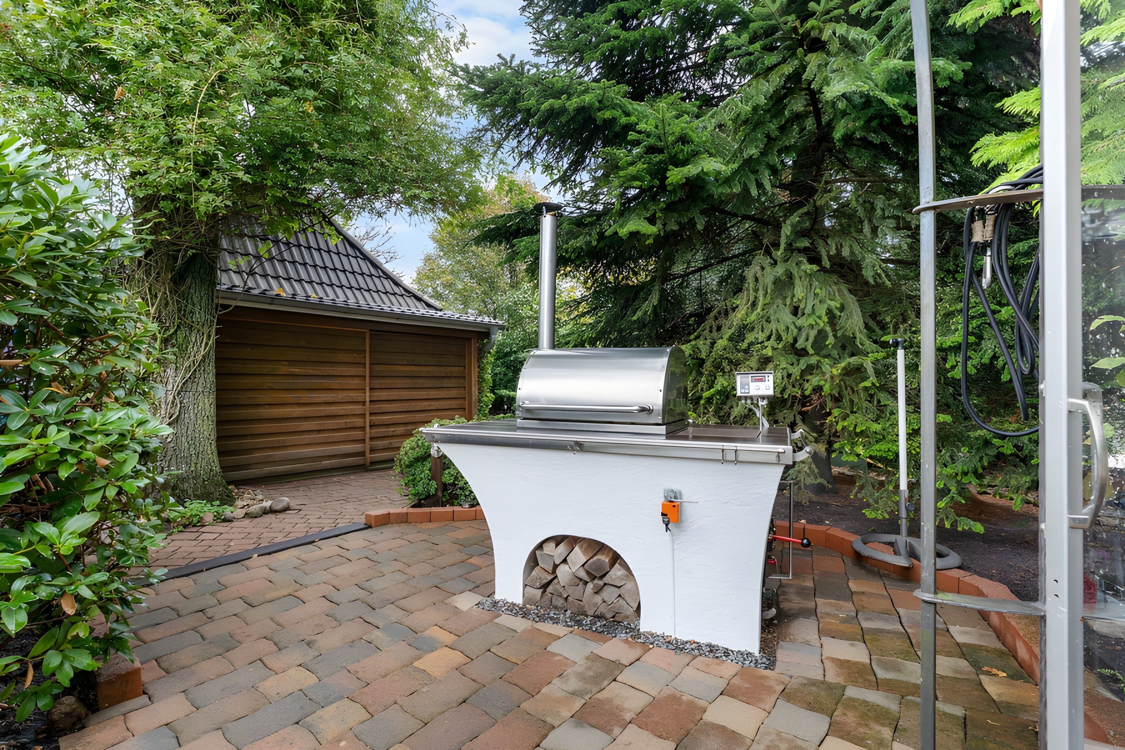 A barbecue grill with a chimney, a wooden shed, and a brick pathway.