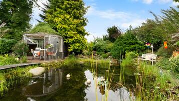 Ein Garten mit Teich, Laube und Bank.