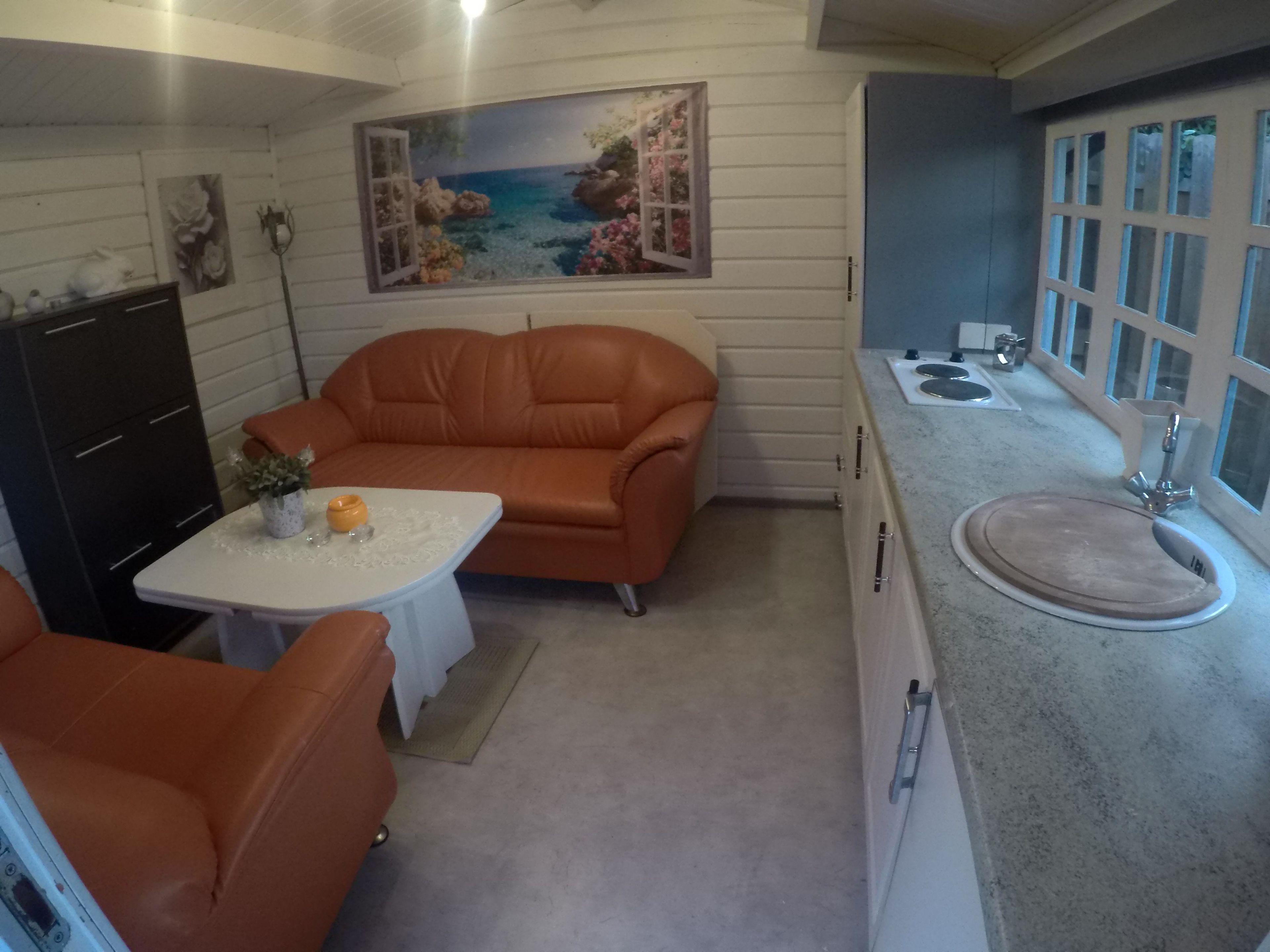 Eine kompakte Küche mit Essbereich, ausgestattet mit einer Couch, einem kleinen Tisch und einem Spülbecken.