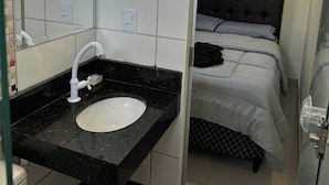 A modern bathroom with a white sink, a mirror, and a black countertop. - EAM COMPLEXO RESIDECIAL Apto 07 (Bela Vista de Goiás)