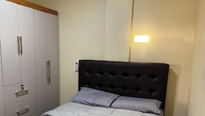 A bedroom with a bed, a wardrobe, and a wall-mounted light. - EAM COMPLEXO RESIDECIAL Apto 07 (Bela Vista de Goiás)