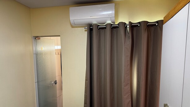 A room with a bed, an air conditioning unit, a door, and a curtain. - EAM COMPLEXO RESIDECIAL Apto 07 (Bela Vista de Goiás)