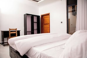 A bedroom with a bed, a wardrobe, a chair, and a door.