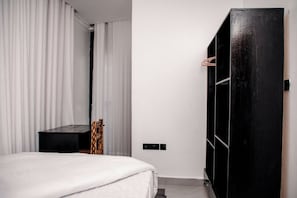 A bedroom with a bed, a wardrobe, and a mirror.