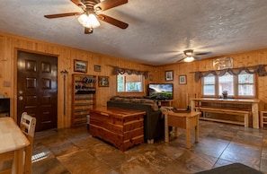 A cozy cabin interior with a wooden interior, a television, a sofa, and a dining table. - Adventurous Cabin with Hot Tub & Fire Pit for Relaxing in Island Park, Idaho (Island Park)
