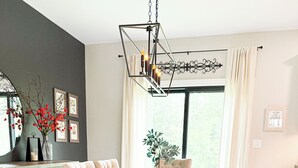 A dining area with a wooden table, cushioned chairs, a bench, a hanging light fixture, and a potted plant. - Modern Farmhouse In Salem (Salem)