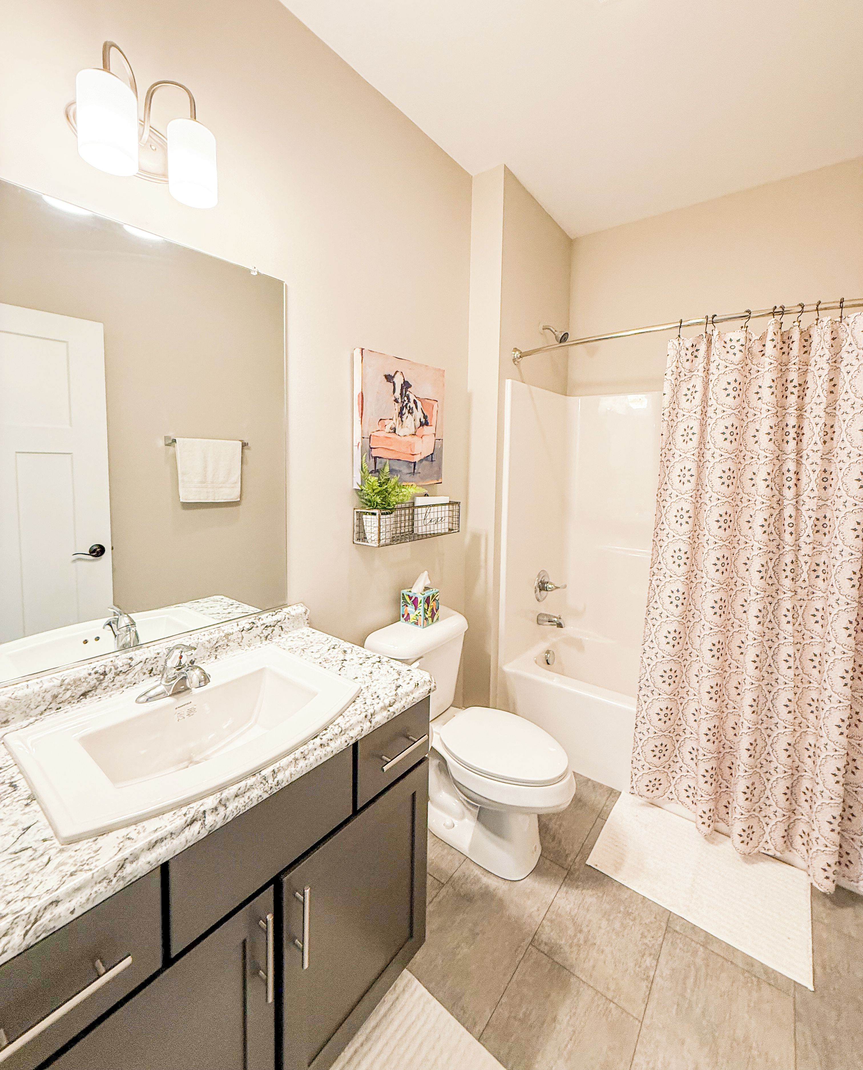 A bathroom with a double sink vanity, toilet, bathtub, and shower curtain.