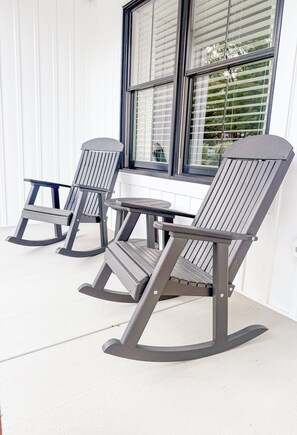 Three rocking chairs with a table on a porch with a window and blinds. - Modern Farmhouse In Salem (Salem)