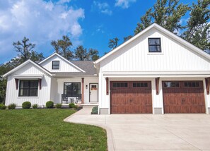 A two-story residential building with a front porch, a garage, and a driveway. - Modern Farmhouse In Salem (Salem)