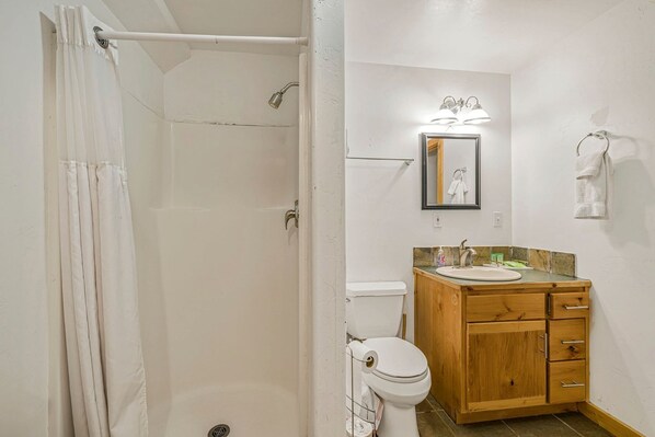 Ein Badezimmer mit Dusche, Toilette, Waschbecken und Holzschrank.