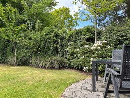 Un jardín con un sendero pavimentado, una mesa y sillas.