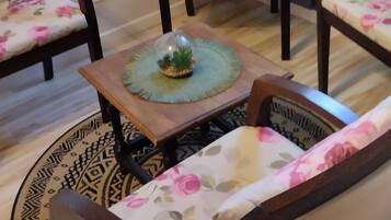A room with a high ceiling, wooden flooring, and floral-patterned furniture including chairs and a sofa.