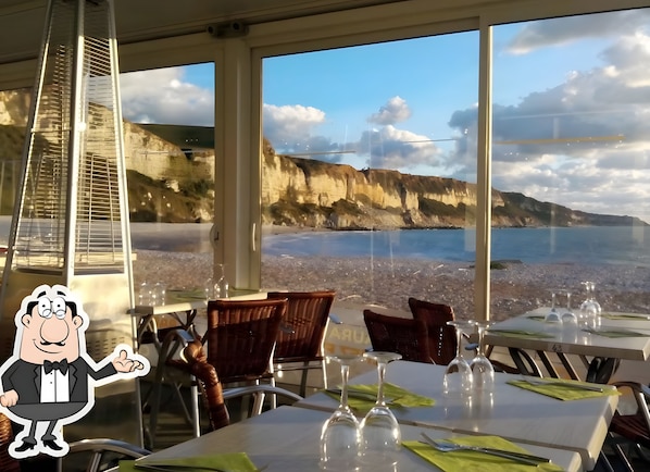 Un restaurante con mesas preparadas para comer, vista al mar y un personaje de caricatura.