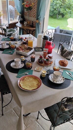 Une table de petit-déjeuner dressée avec divers aliments et boissons, une cafetière et une théière.