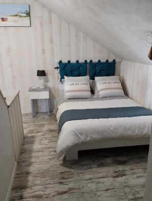 Une chambre à coucher avec un lit, une table de chevet, une lampe et un tableau au mur.