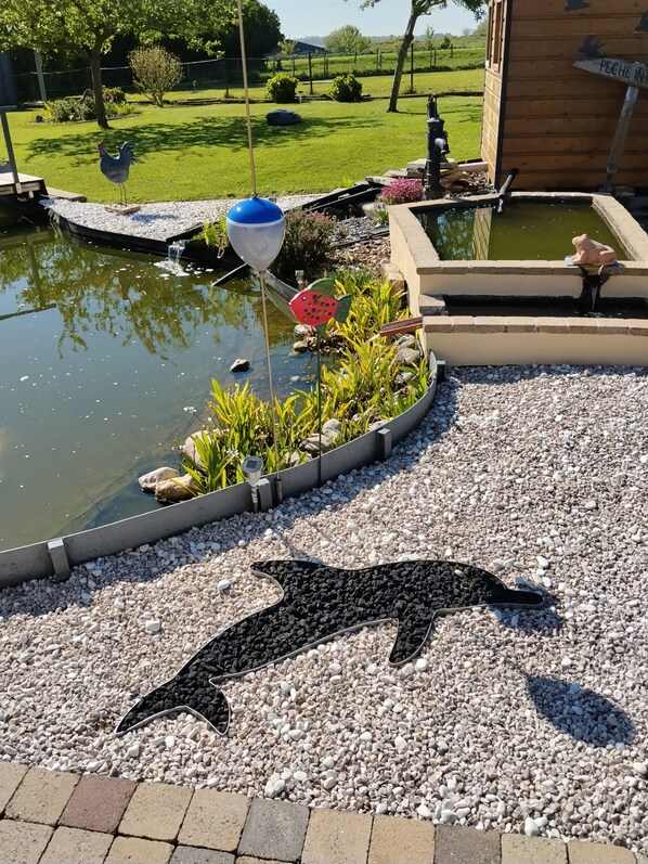 Un jardin avec un étang, une statue de paon et un panneau en forme de paon.