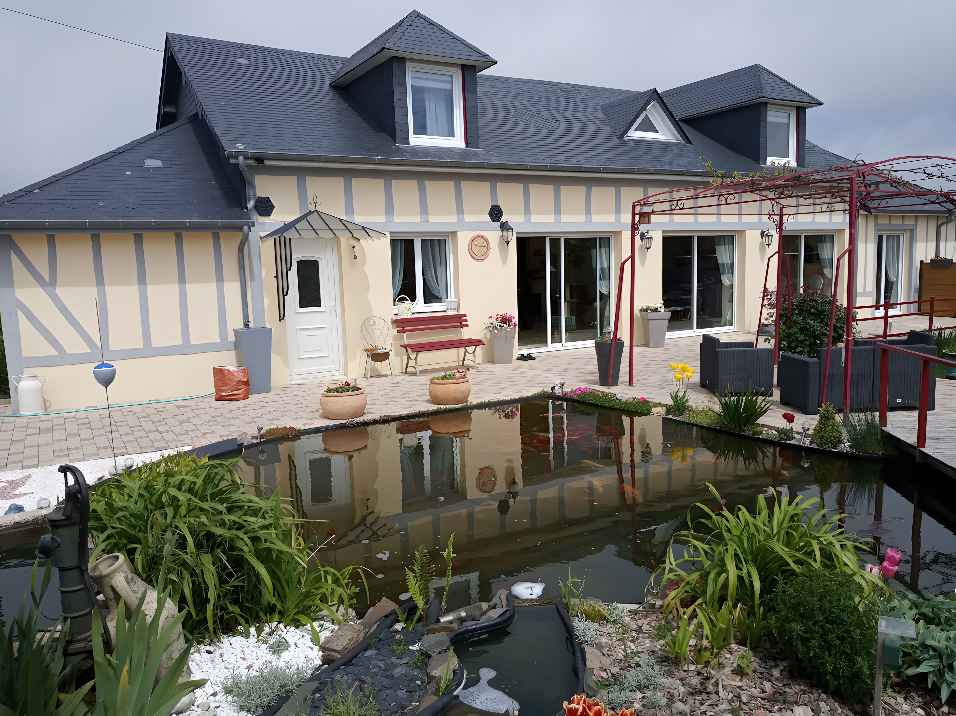 A house with a pond, outdoor seating, and a garden.