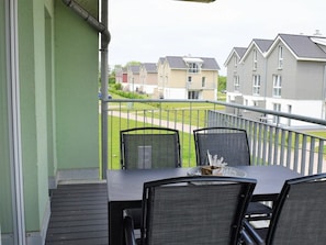 A balcony with a table and chairs, overlooking a residential area with houses. - 47.1.n Waterkant (Wangerland)