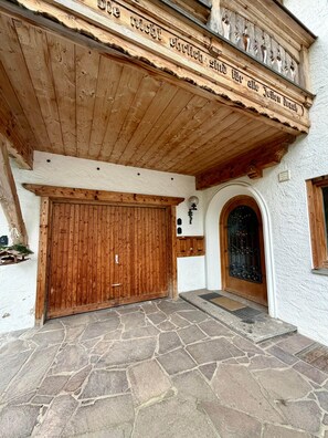 Ein Gebäude mit einer Holzfassade, einem gepflasterten Eingangsbereich und einer großen Holztür.