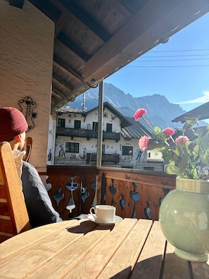 Ein Holztisch mit Tasse und Untertasse, eine Vase mit Blumen und Blick auf Berghäuser.