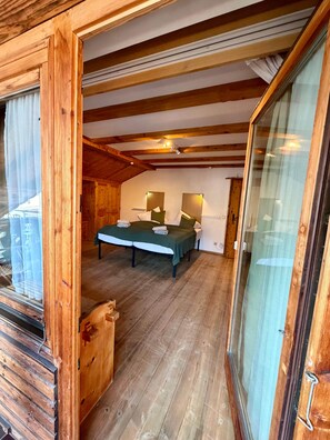 Un interior de madera con una cama, mesitas de noche y un ventanal.
