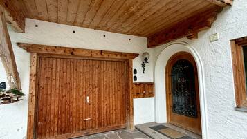 Ein Gebäude mit einer Holzfassade, einem gepflasterten Eingangsbereich und einer großen Holztür.