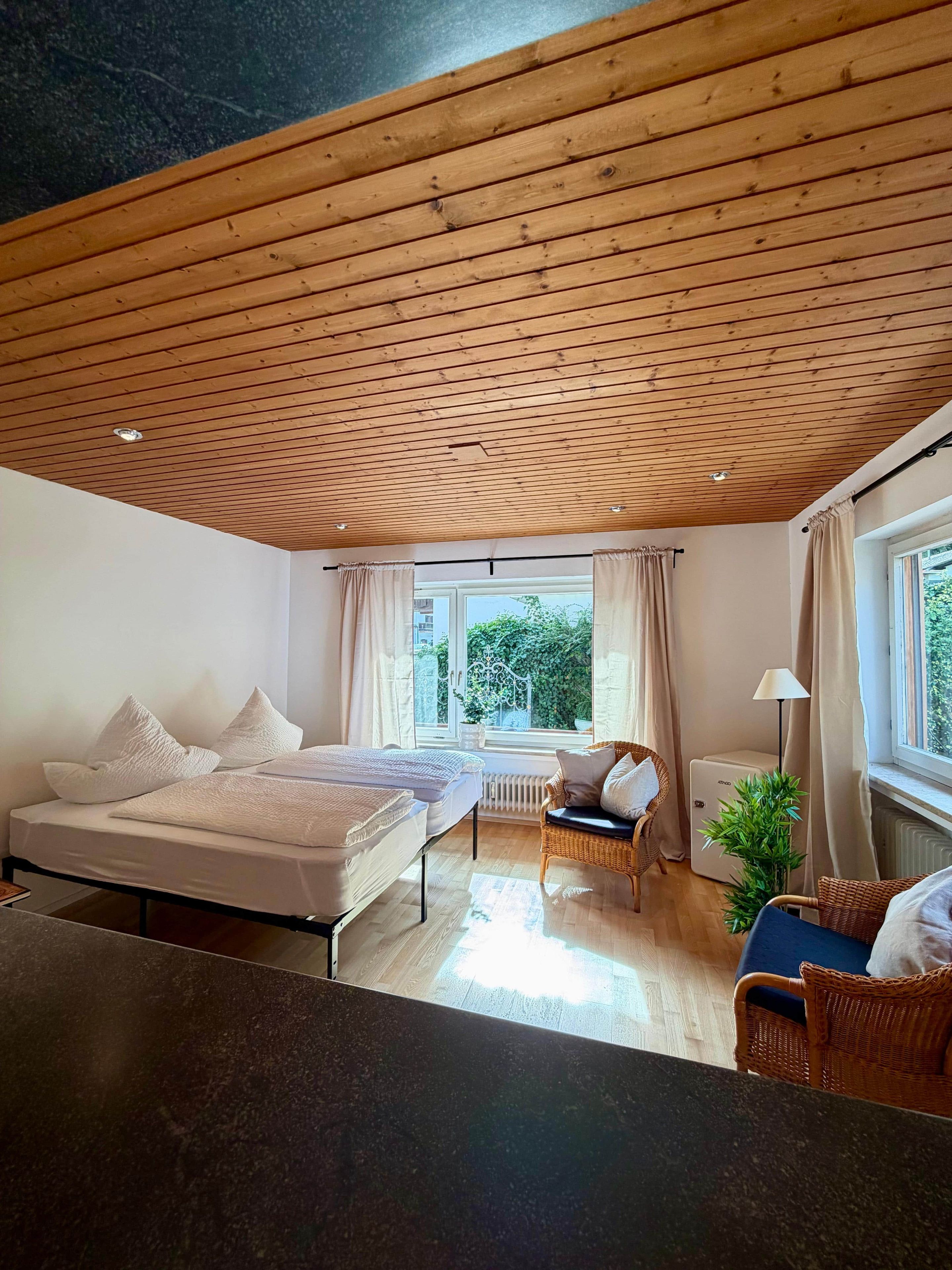 Ein Schlafzimmer mit einem Bett, einem Sessel, einer Heizung und einem Fenster mit Vorhängen.