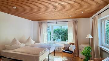 Ein Schlafzimmer mit einem Bett, einem Sessel, einer Heizung und einem Fenster mit Vorhängen.