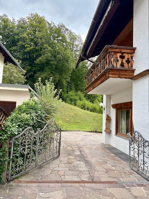 Ein gepflasterter Weg führt zu einem Gebäude mit einem hölzernen Balkon und einer Statue an der Wand.