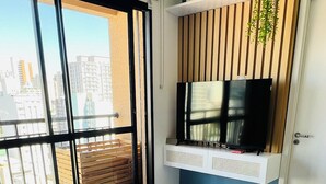 A modern bedroom with a large bed, a television mounted on a wall, and a view of the city through large windows. - New and Modern • Partridges • 800m Allianz Parque • (São Paulo)