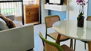 A modern living room with a sofa, dining table, chairs, a TV, and a balcony with a city view. - New and Modern • Partridges • 800m Allianz Parque • (São Paulo)