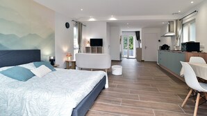 Ein modernes Schlafzimmer mit einem großen Bett, einem Fernseher und einer Essecke mit Tisch und Stühlen.