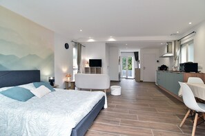 Un dormitorio moderno con una cama grande, un televisor y una zona de comedor con mesa y sillas.