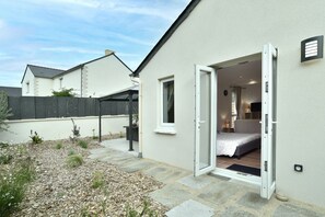 Una casa de un piso con un dormitorio que tiene una cama, mesita de noche y lámpara.