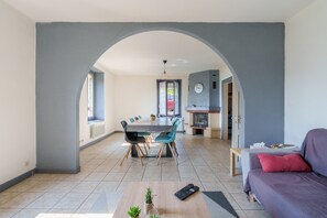 A modern living space with an open-plan design, featuring a dining area, a sofa, and a fireplace. - Les Souvenirs du Reucy - vue montagne (La Bresse)