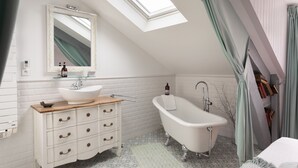 Une salle de bain avec une baignoire sur pieds, un meuble-lavabo avec des tiroirs, un miroir et une fenêtre de toit.