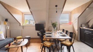 Un coin repas avec une table dressée pour quatre personnes, un canapé, une table basse et un téléviseur.