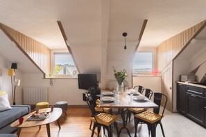 Een eetruimte met een tafel voor vier personen, een bank, een bijzettafeltje en een televisie.