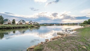 A lakeside view with a picnic table and houses in the background. - Pagosa Springs Resort | Hot Springs, Lake & Pools (Pagosa Springs)