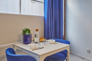 A small dining area with a table, chairs, a potted plant, a bottle, and a plate of food. - Goshen - studio au coeur du centre historique (Bergerac)