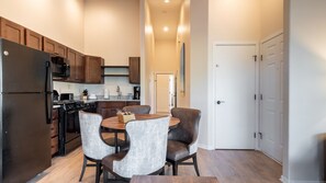 A modern kitchen with dark wooden cabinets, a stainless steel refrigerator, and a dining area with a round table and four chairs. - Pagosa Springs | Hot Tub & Mountains | 3BR Sleeps 8 (Pagosa Springs)