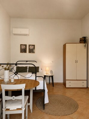 A compact bedroom with a bed, bedside table, lamp, and a wardrobe.