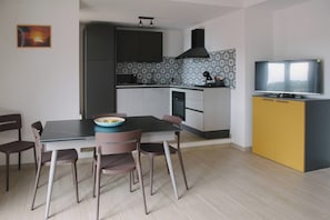 Eine moderne Küche mit Esstisch, Stühlen und einem Fernseher.