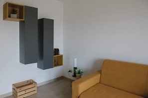 Ett minimalistiskt vardagsrum med en soffa, en trälåda och inbyggda hyllsystem.