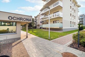 A modern building with a sign reading 'OCHRONA' and a well-maintained lawn area. - Łódź | Karola Borowieckiego 1 | Spacious Apartment | Terrace (Łódź)